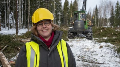 Specialforskare Saija Huuskonen står framför en skogsmaskin.