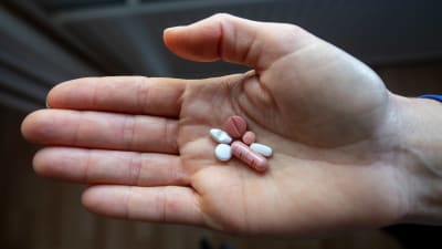 En person håller i antidepressiva läkemedel i sin hand. Totalt sex piller.