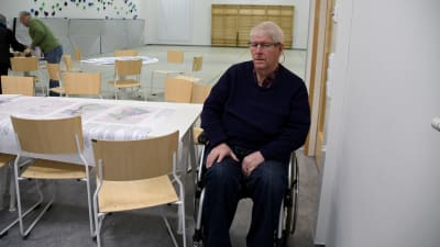 En man sitter i en rullstol i dörröppningen till en gymnastiksal.