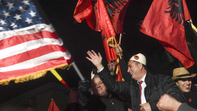 Albin Kurti ses i mitten av bilden, omgiven av flaggor och personer som firar. 