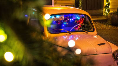 Festlig julbelysning och en gammaldags bil på gatan