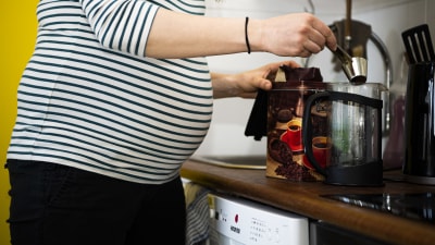 En gravidperson kokar kaffe.