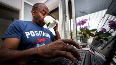 En man distansarbetar och dricker kaffe.