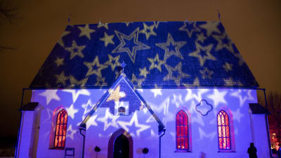 Borgå domkyrka är upplyst av stjärnor, inifrån kyrkosalen flöder varmt rött ljus.