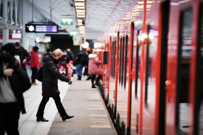 Människor i munskydd går vid en metro i Helsingfors.