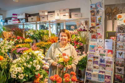 Saara Manninen, ägare och drivare av blomaffären "Porvoon Kukkapalvelu", som poserar med en blombukett i sin affär.