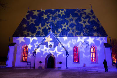 Borgå domkyrka är upplyst av stjärnor, inifrån kyrkosalen flöder varmt rött ljus.