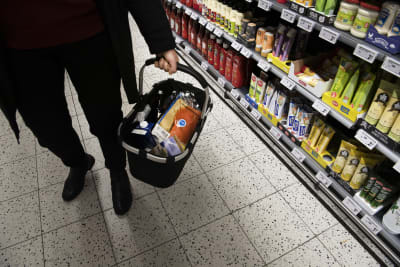 En kund med en full inköpskorg i en matbutik.