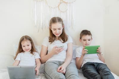 tre barn tittar på olika skärmar