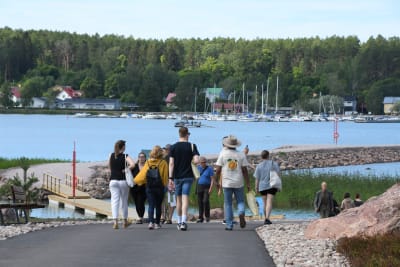 Besökare går ner för en backe med Lovisaviken i bakgrunden.