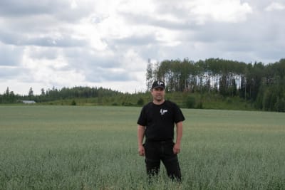 Christian Jensen vid en åker i Paipis, skog i bakgrunden. 