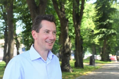 En man i blå kragskjorta ler och tittar mot framtiden.