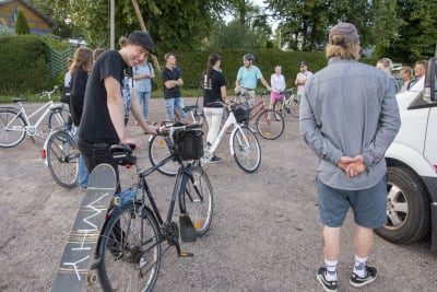 Jaakko Aalto står i en grupp med människor, bak på hans cykel finns hans skejtboard.