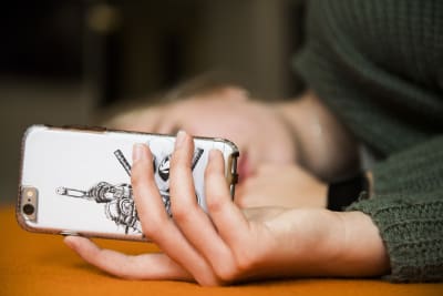 Närbild av en vit telefon som en ung flicka håller i. 