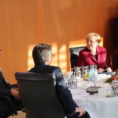 Hymyileät Obama ja Merkel pyöreän pöydän ääressä. 