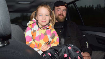 ett barn, flicka och en vuxen man (pappan) sitter i baksätet i en personbil.