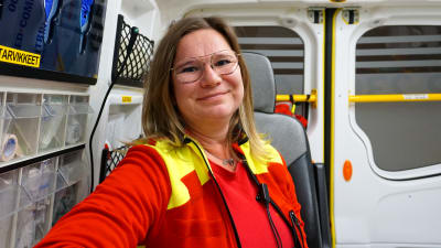 Kvinna i röda kläder sitter i en ambulans.