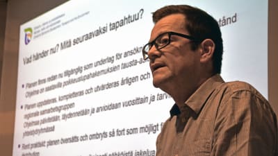 Vincent Westberg framför en vit skärm med text på.