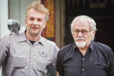 Pavel och Jürgen Kempf tittar in i kameran. Papegojan Iivo sitter på Pavels axel.
