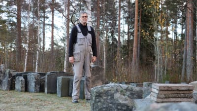 Församlingsmästare Olav Klemets står bland gravstenar som plockats bort från gravarna på Åsändans begravningsplats i Lappfjärd