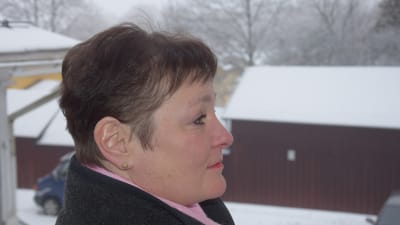 Kvinna i profil i förgrunden framför snöigt landskap.