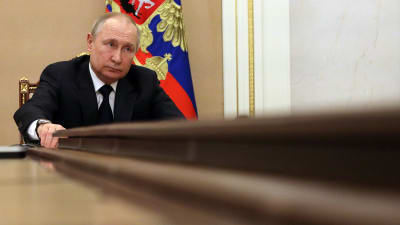 Vladimir Putin sitter vid ändan av ett bord.
