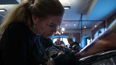 Blond kvinna tatuerar en kund