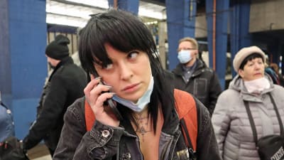 En kvinna står på en tågperrong och talar i mobilen.