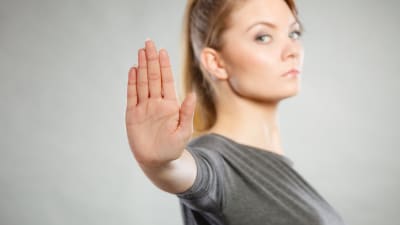 Kvinna håller upp en hand för att signalera stopp.