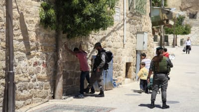 Israelisk soldat kroppsvisiterar palestinsk tonåring i Hebron på palestinska Västbanken