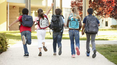 Barn med ryggsäck på väg till skolan.