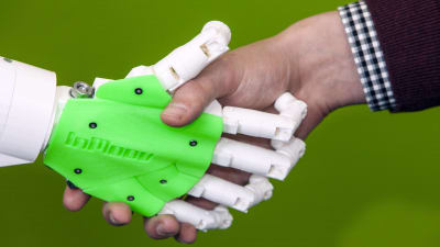 En robothand som skakar hand med en människohand.