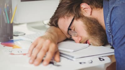 Man sover lutad mot sitt arbetsbord