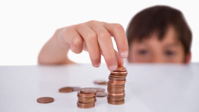 Pojke staplar mynt på ett bord.