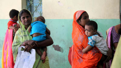 Mammor köar för vård för sina barn på ett sjukhus i Calcutta