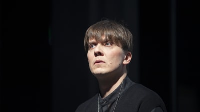 Närbild av skådespelaren Eero Riitala mot en svart bakgrund.