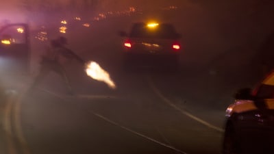 En polisman använder sin pistol för att skjuta av en elledning på en landsväg