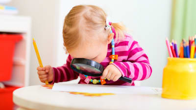 Ett barn tittar på ett papper genom ett förstoringsglas.