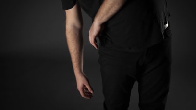 Bild på Jonas torso, där händerna hänger och dinglar mot marken. Huvudet syns inte, i en mörklagd studio. 