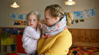 Dagislärare håller två-årig flicka i famnen