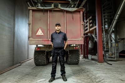 En man i mörka arbetskläder står framför en spannmålskärra