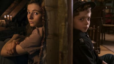Jojo och Elsa sitter lutade mot varsin sida av en vägg.