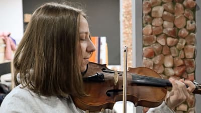 En tonårsflicka ler och spelar violin.