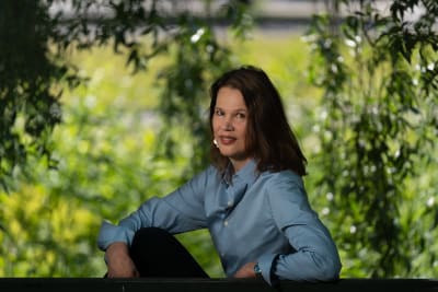 Elina Pylkkänen sitter på en bänk i en somrig park.