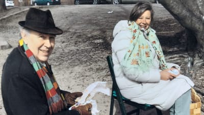 Två författare ute på Valborgs-picknick sitter på varsin stol och ler emot kameran.