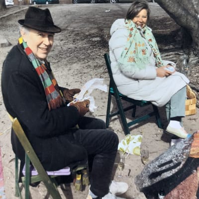 Två författare ute på Valborgs-picknick sitter på varsin stol och ler emot kameran.