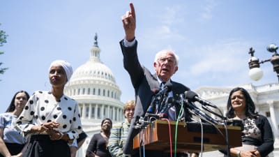 Bernie Sanders framför mikrofoner utanför kongressen med pekfinger i luften.