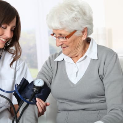 läkare mäter blodtrycket på äldre patient