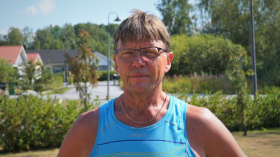 Man i blå ärmlös t-skjorta står på en bakgård.