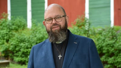Karl af Hällström framför ett rött lider och gröna buskar. Han småler.